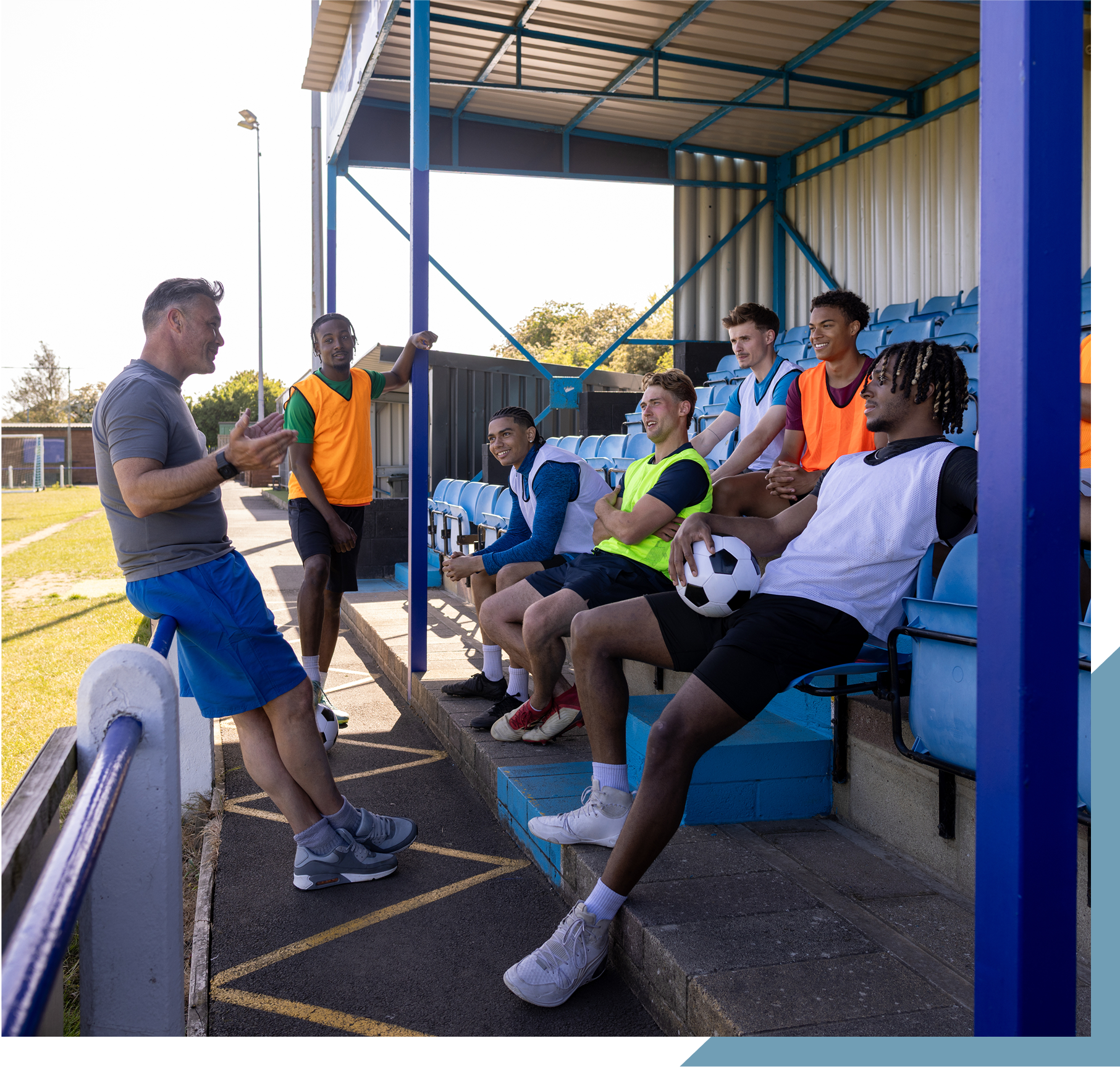 Coach talking to soccer team on benches.
